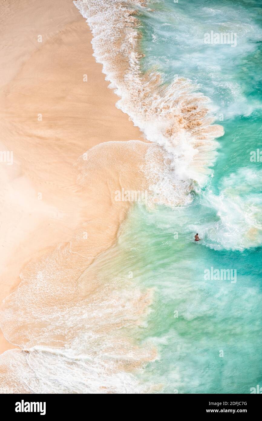 View from above, stunning aerial view of an unidentified person walking on a beautiful beach bathed by a turquoise sea. Kelingking beach, Nusa Penida. Stock Photo
