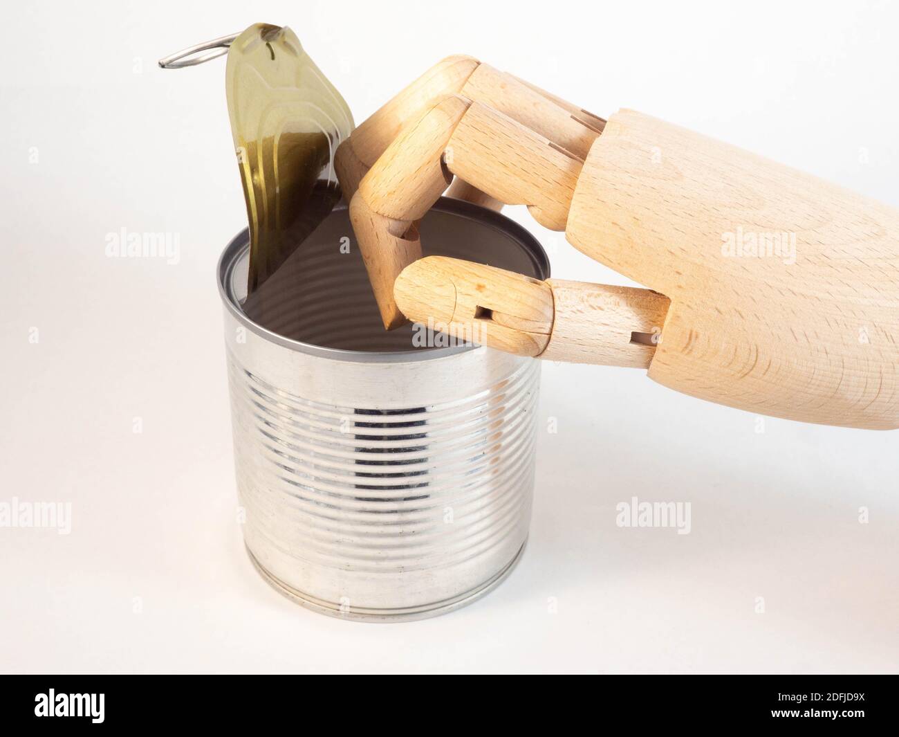 A wooden hand that is above a tin can. Concept around catering and consumption. Stock Photo