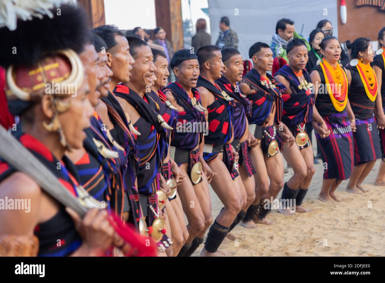 A group of naga tribesmen and women dressed in their traditional attire dancing during Hornbill festival in Nagaland India on 2 December 2016 Stock Photo