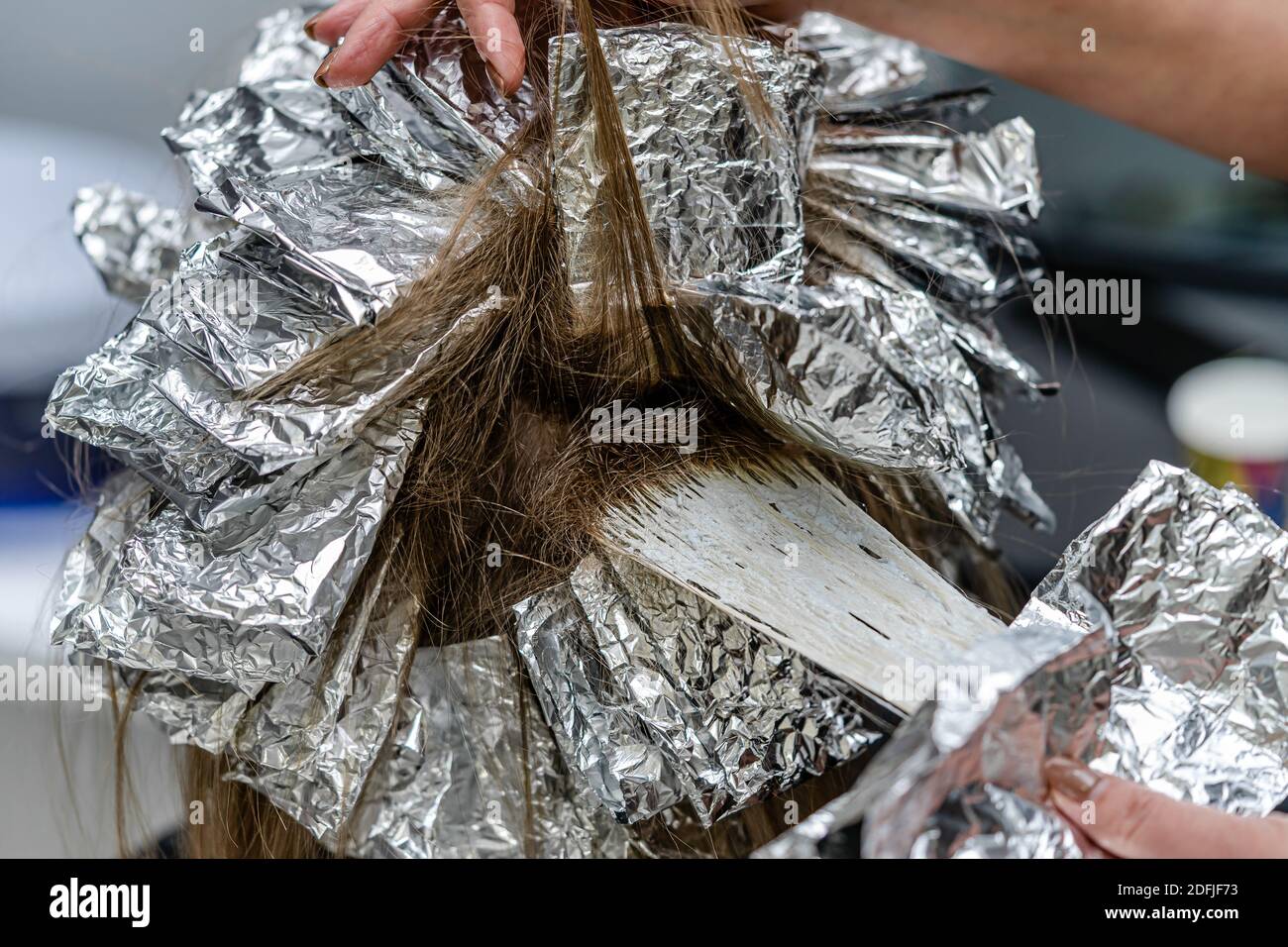 Hair stylist checking models hair during bleaching process. Trendy hair