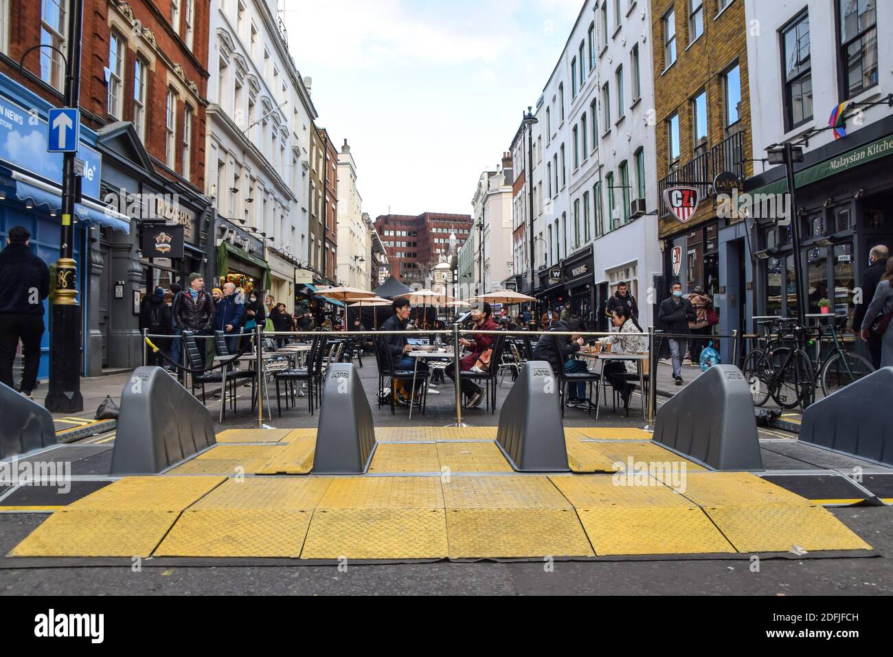 A view of a traffic barrier and restaurants in Old Compton Street, Soho