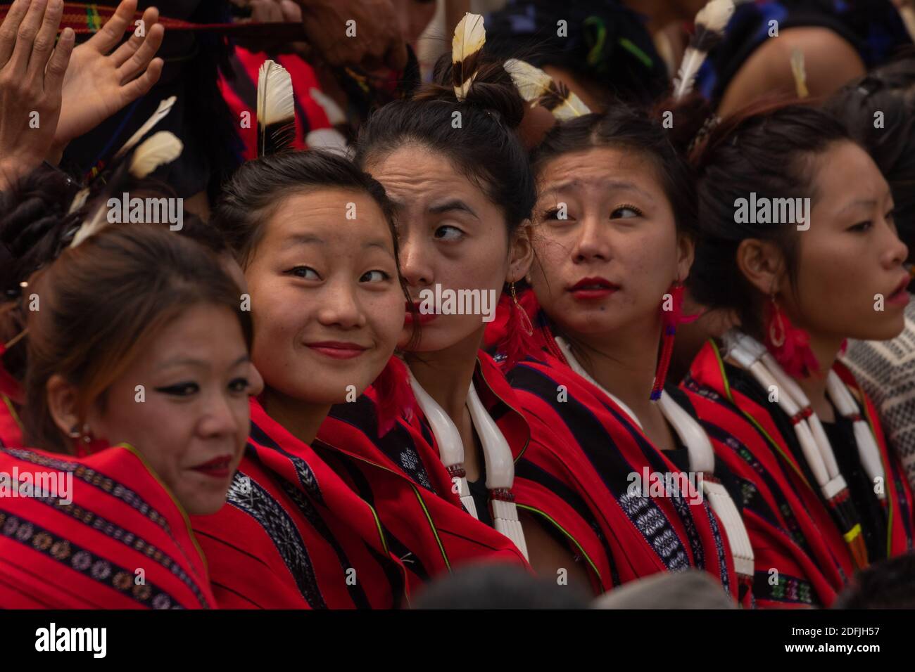 Young Naga girls siting together wearing colorful attire and shawls in Kisama Heritage village in Nagaland India on 3 December 2016 Stock Photo