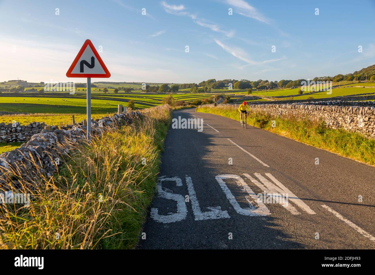 View of dry stone walls and cyclist on country lane, Foolow, Derbyshire Peak District, England, United Kingdom, Europe Stock Photo