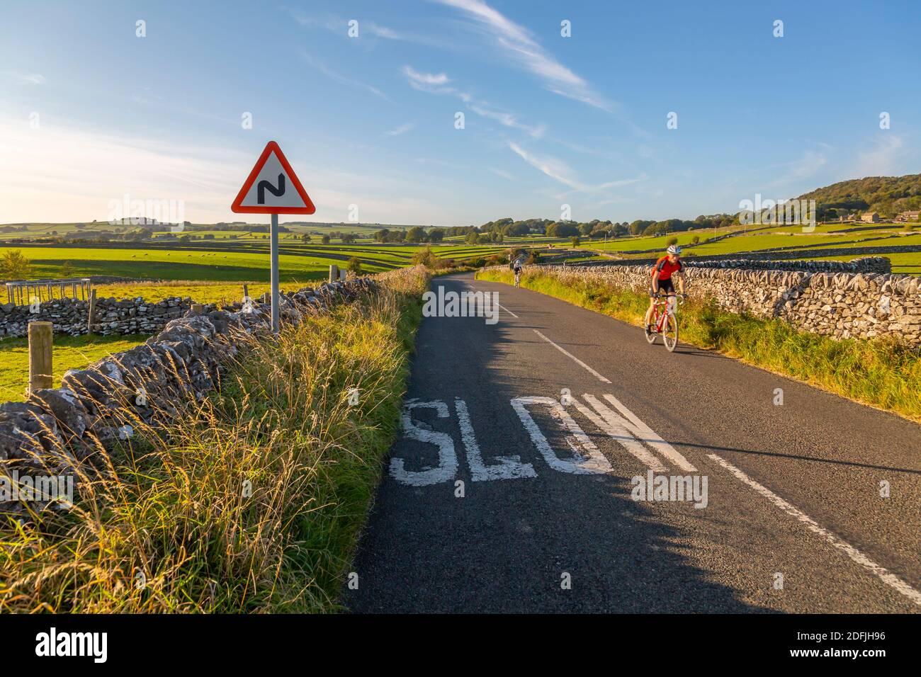 View of dry stone walls and cyclist on country lane, Foolow, Derbyshire Peak District, England, United Kingdom, Europe Stock Photo