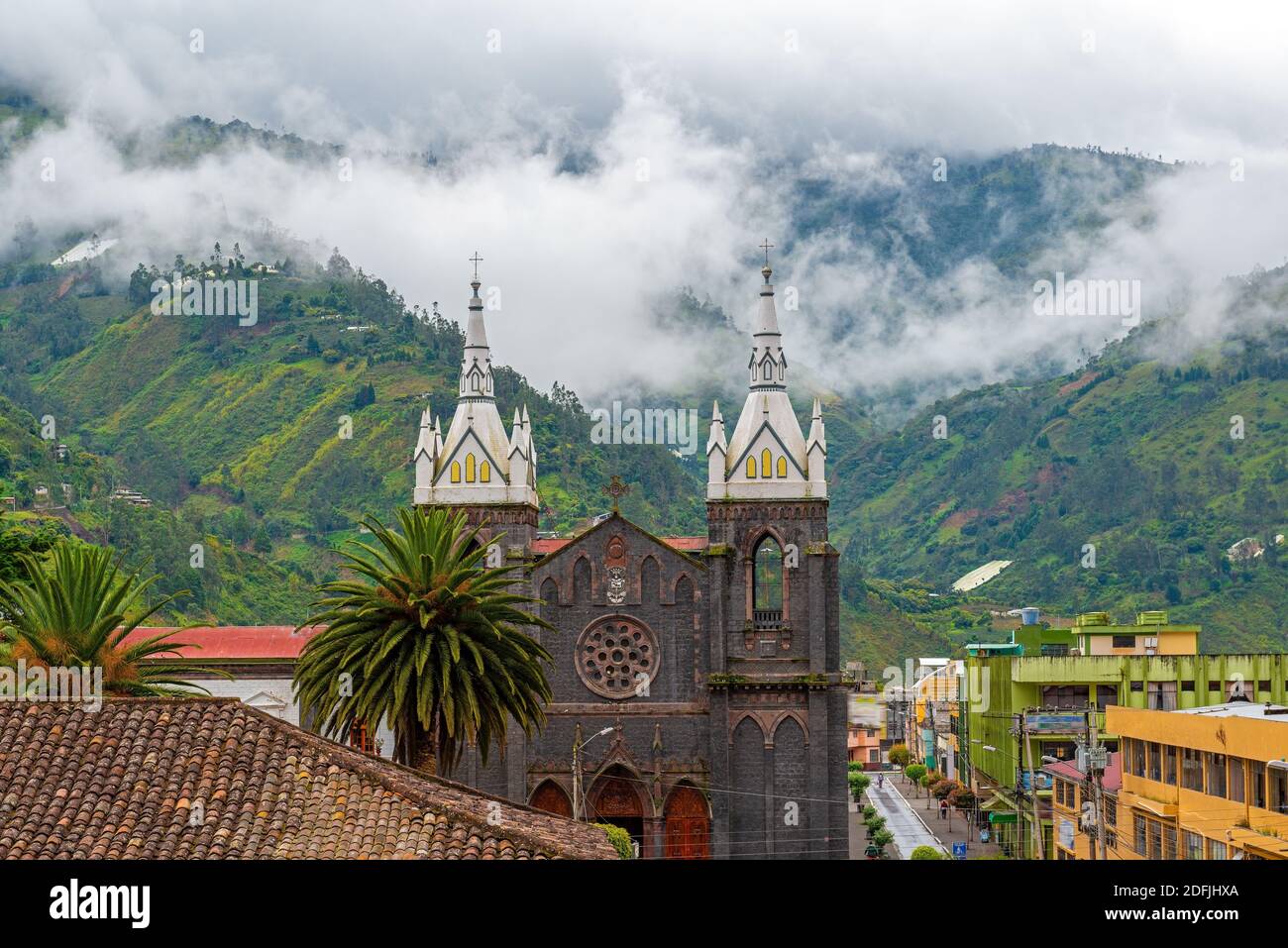 Aerial cityscape of Banos de Agua Santa located in the cloud forest with the bell towers of the Holy Water Virgin Church, Ecuador. Stock Photo
