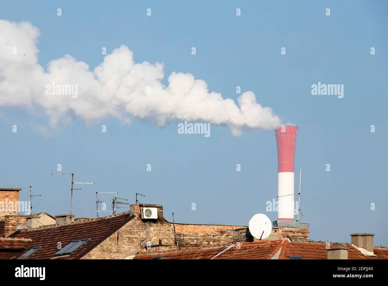Belgrade, Serbia - December 1, 2020: Heating and power station chimney smokestack in red and white stripes, with smoke, in an old residential part of Stock Photo