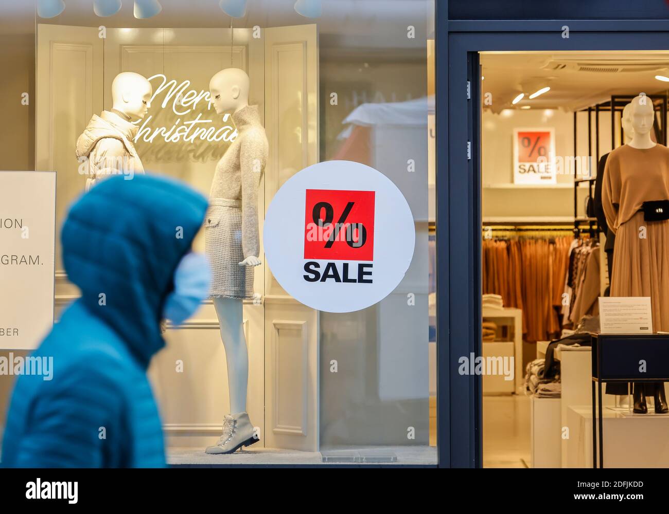 Essen, Ruhr Area, North Rhine-Westphalia, Germany - Shop window of a fashion store at Christmas time with special offers, passer-by with protective ma Stock Photo