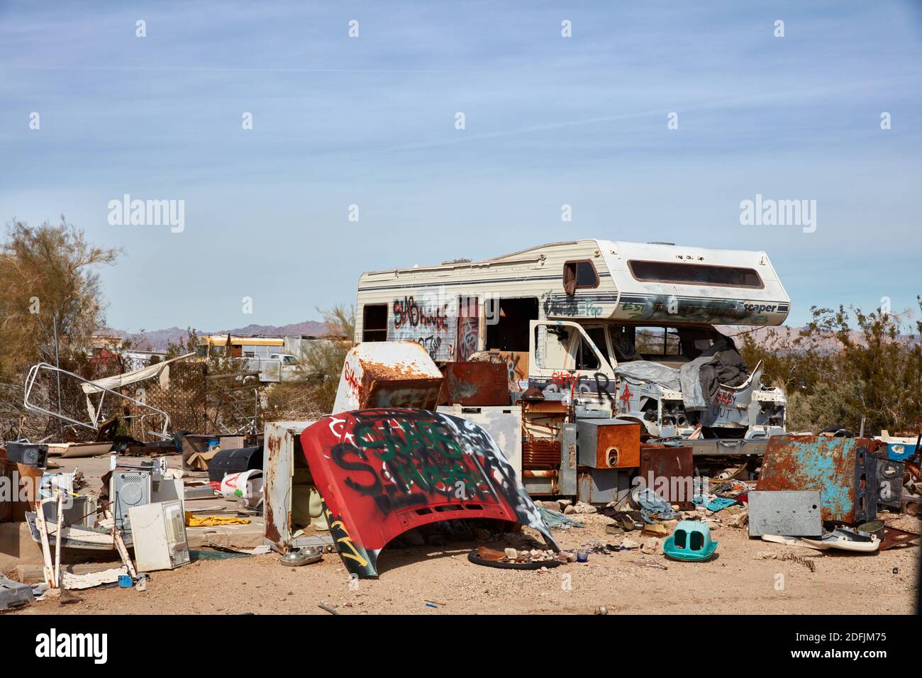 Abandoned RV sitting among discarded appliances and car parts in Slab City, California Stock Photo