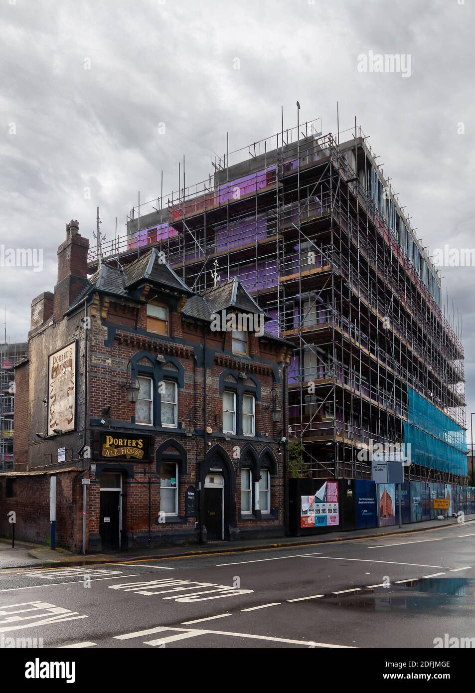 A closed Porters Ale House pub  in front of a high rise apartment block construction in Warrington, Cheshire Stock Photo