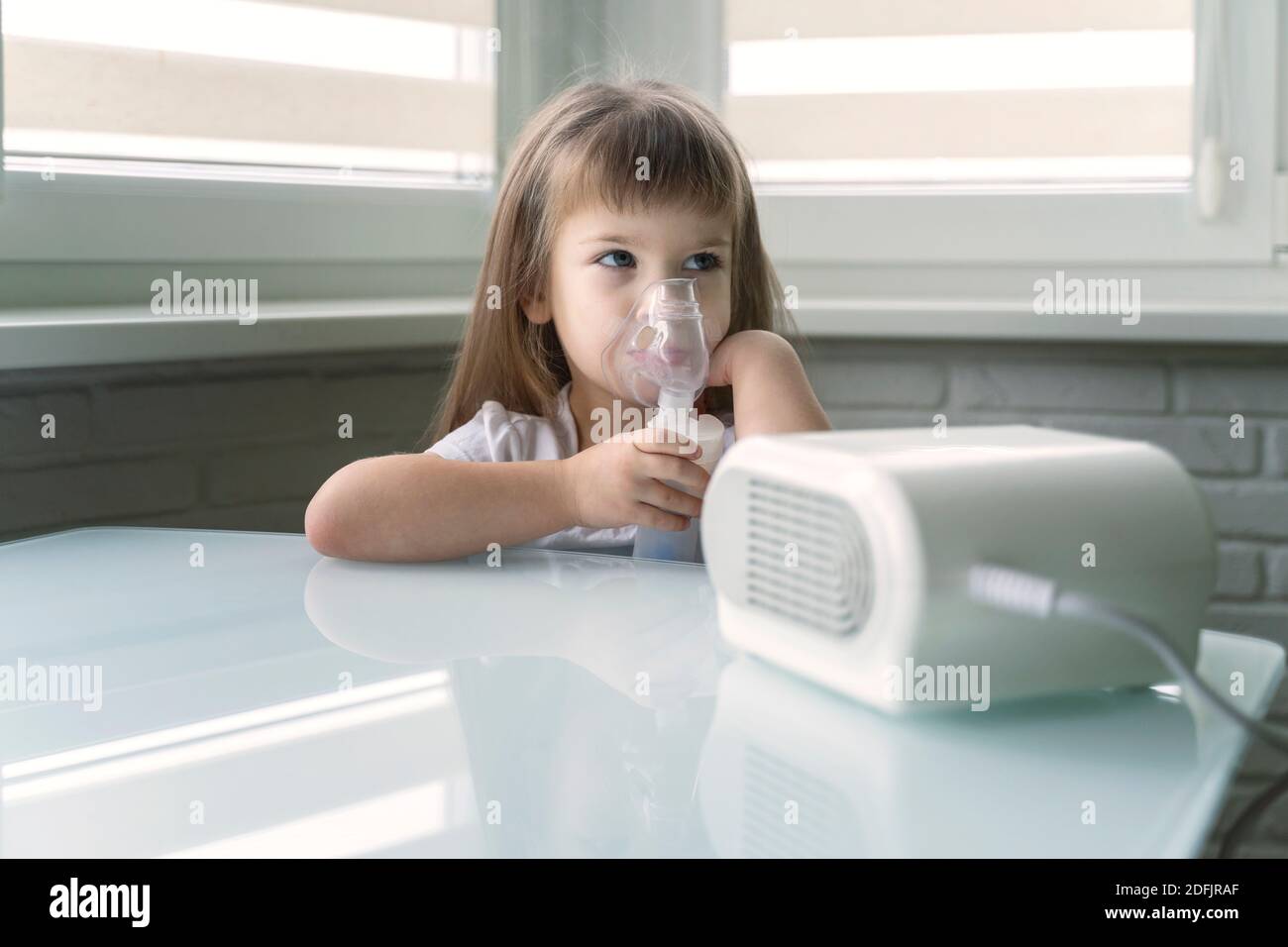 little girl is being treated with a nebulizer at home. pneumonia ...