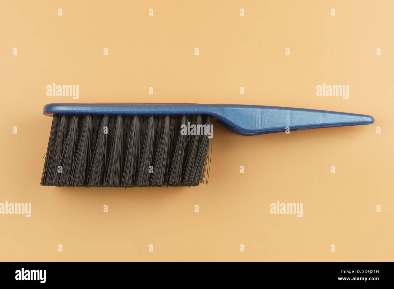 Black brush with blue handle on beige background. Flat lay Stock Photo
