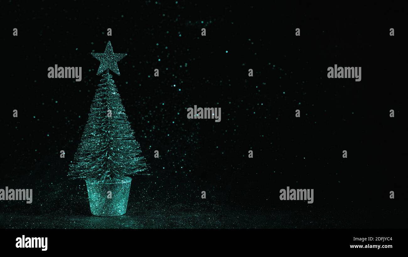 Small silver toy fir tree with star on long defocused glitter ...