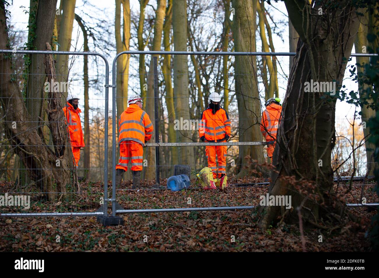 Wendover, Buckinghamshire, UK. 1st December, 2020. HS2 contractors putting up a high security fence in woodlands in Wendover that they have compulsorily purchased. HS2 workers were filling the post holes in the woodland floor with concrete. The controversial HS2 project puts 693 wildlife sites, 33 SSSIs and 108 ancient woodlands at risk. Credit: Maureen McLean/Alamy Stock Photo