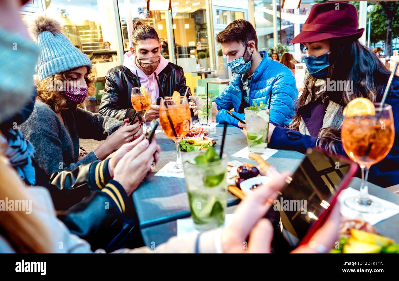 Millenial people using mobile smart phones at cocktail bar - New normal lifestyle concept with friends on contact tracing app during pandemic Stock Photo