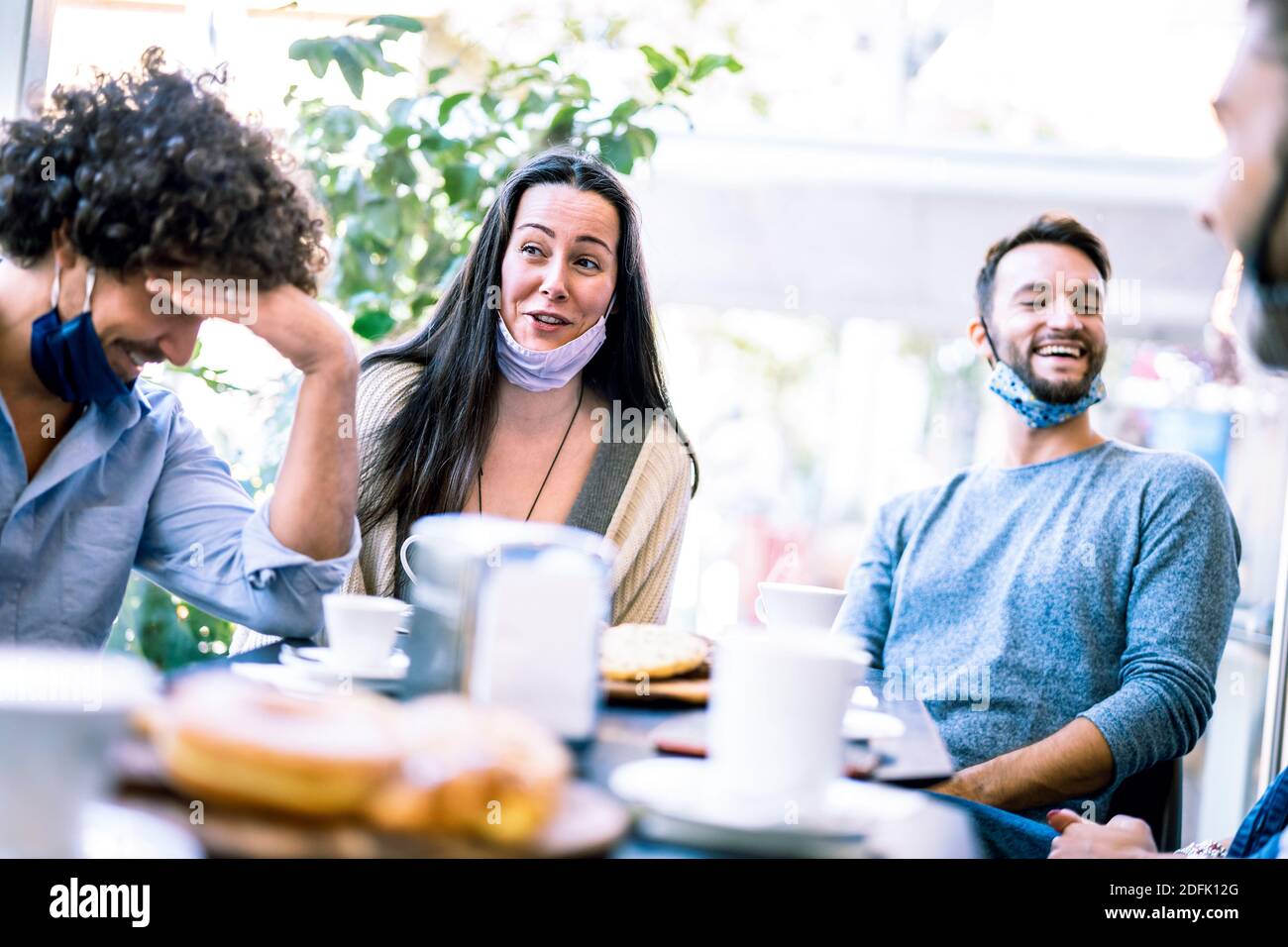 Friends having fun talking at coffeeshop - Young milenial people socializing together at restaurant cafeteria - New normal lifestyle concept Stock Photo