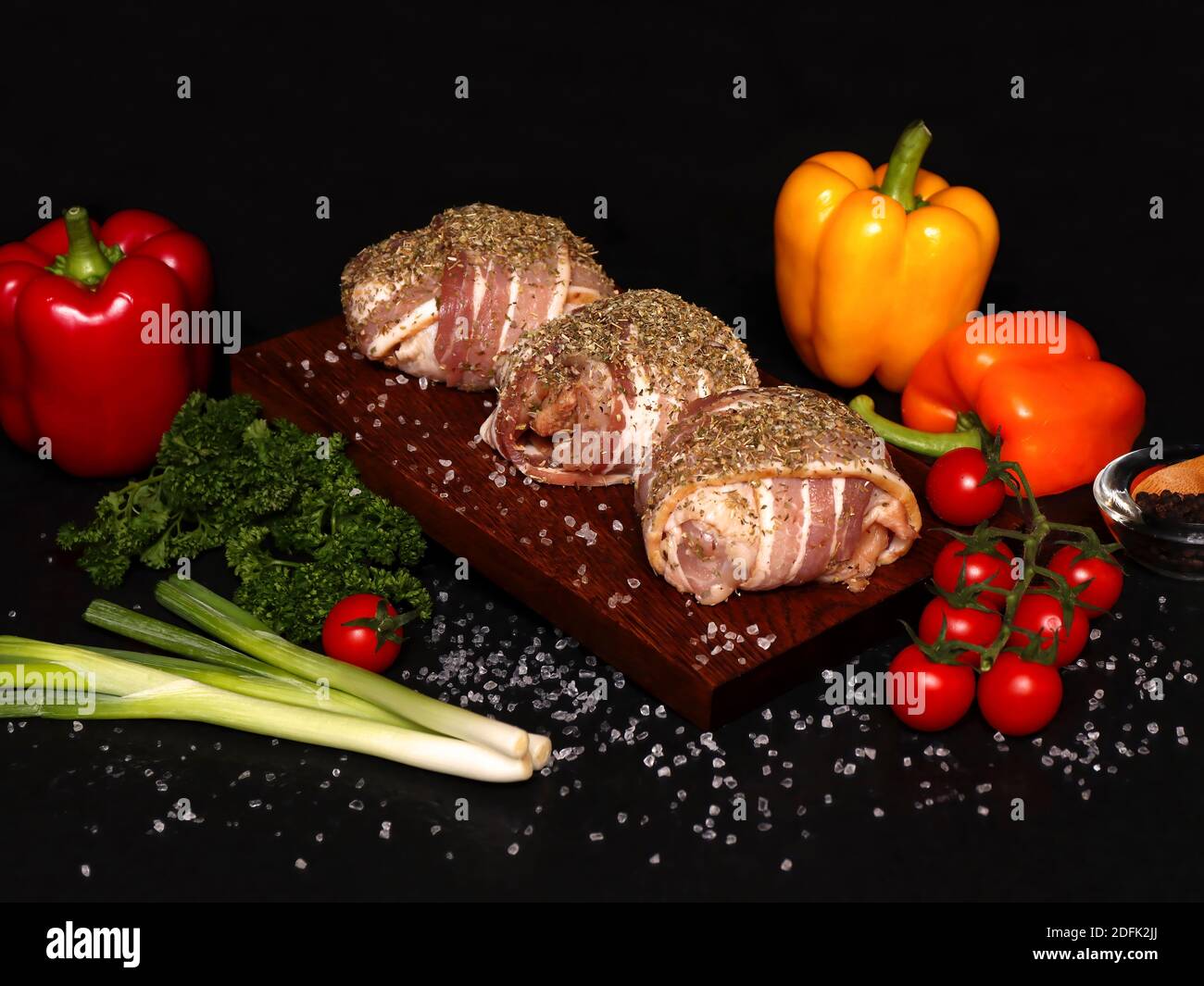 chicken thighs wrapped in bacon on a wooden board ready to cook Stock Photo