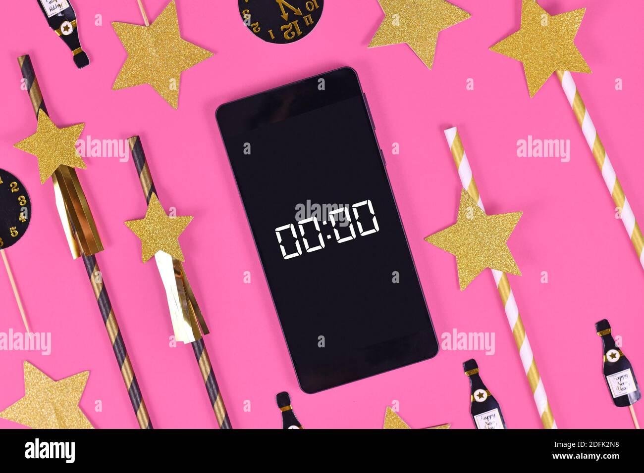New Year Silvester celebration concept with smart phone with timer countdown to midnight between party items like paper straws and paper champaign bot Stock Photo