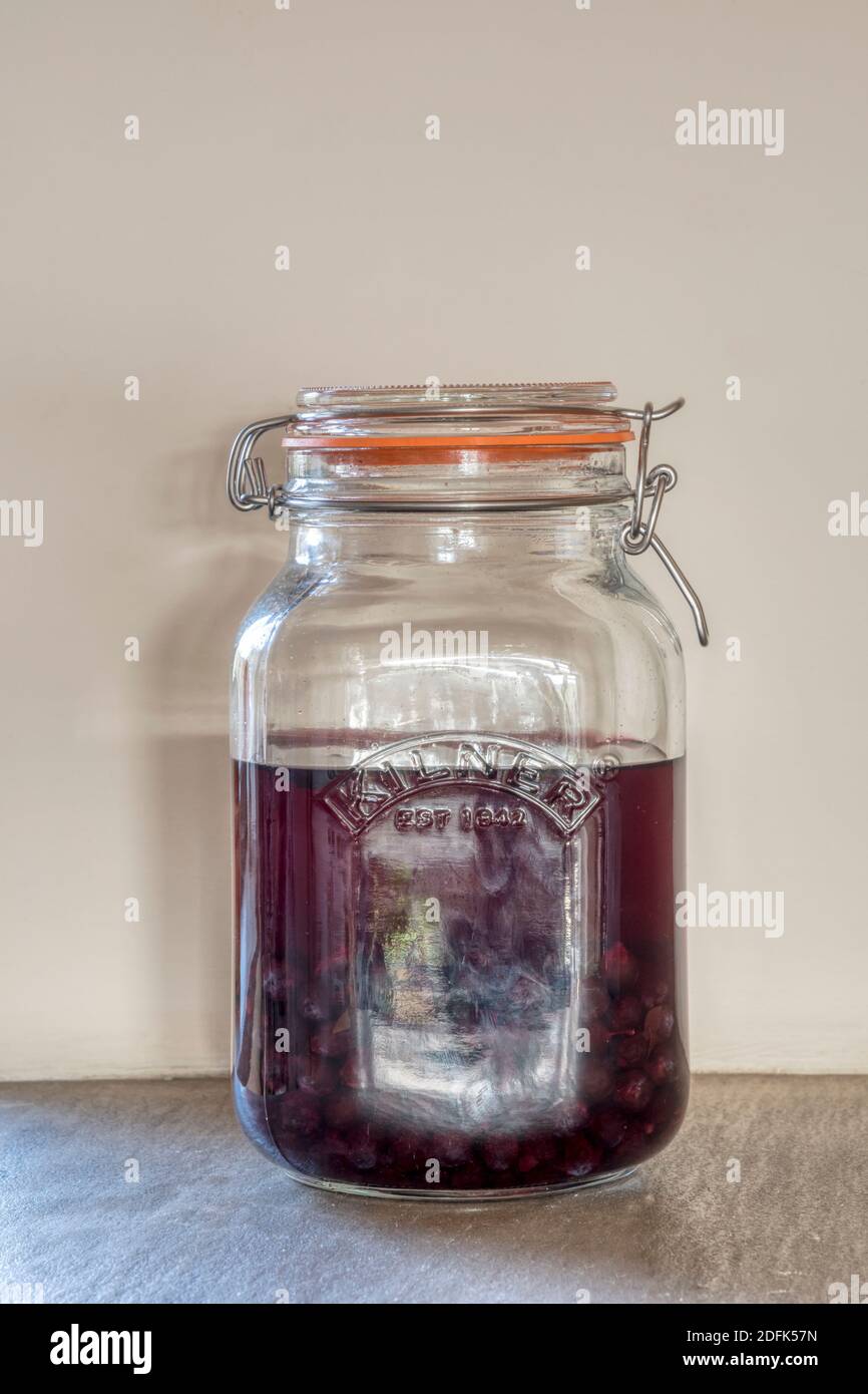 A kilner jar of sloe gin being prepared for drinking at Christmas. Stock Photo