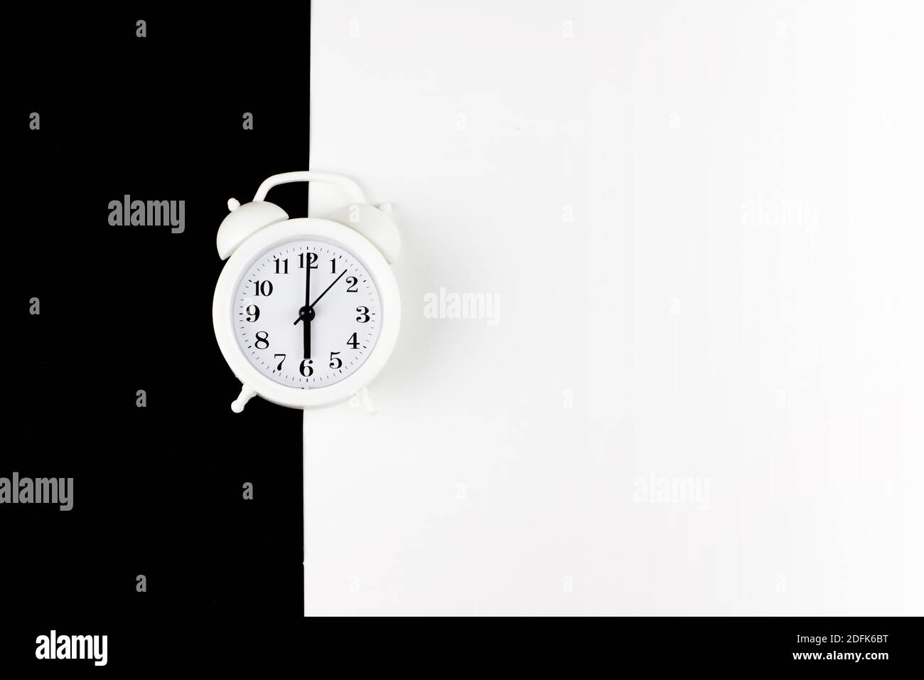 Alarm clock on two tone Black and white paper. Timer, sleep. Top view, place for text Stock Photo