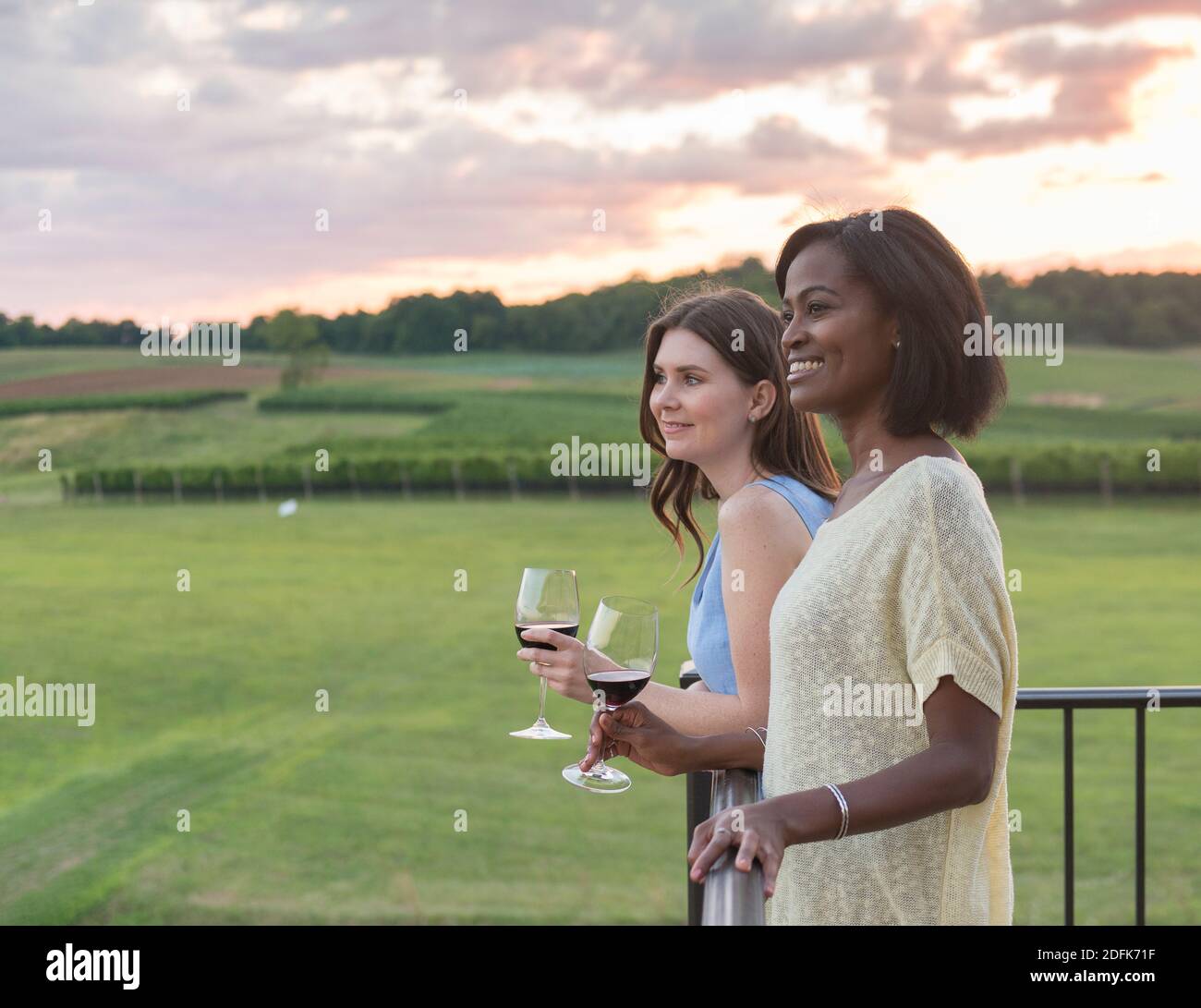 Young women drink wine together on a balcony at a winery. Stock Photo