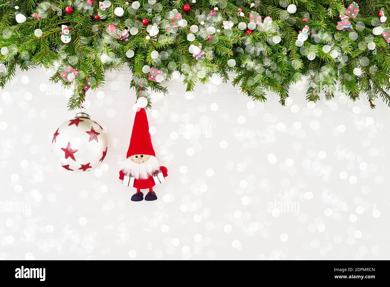 Christmas fir tree branch with Santa and decoration on white wooden background. Copy space, top view Stock Photo