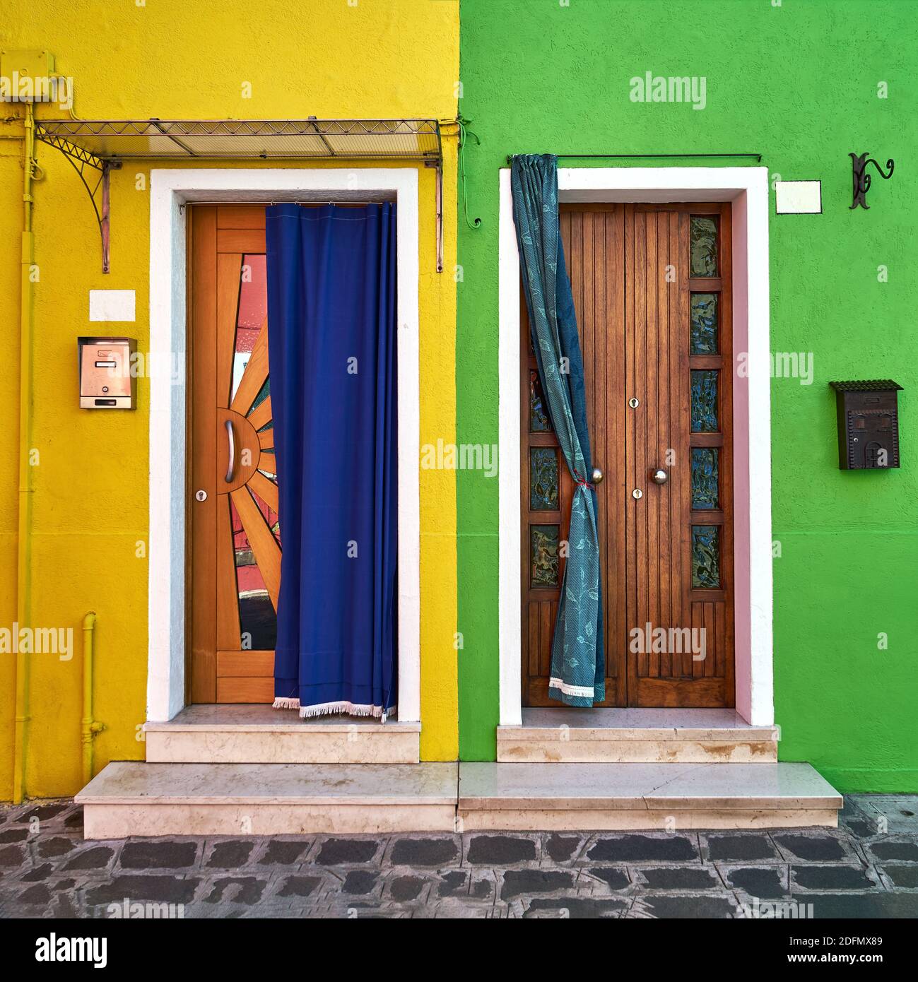 Two doors on the bright facade of the houses. Italy, Burano, Venice Stock Photo
