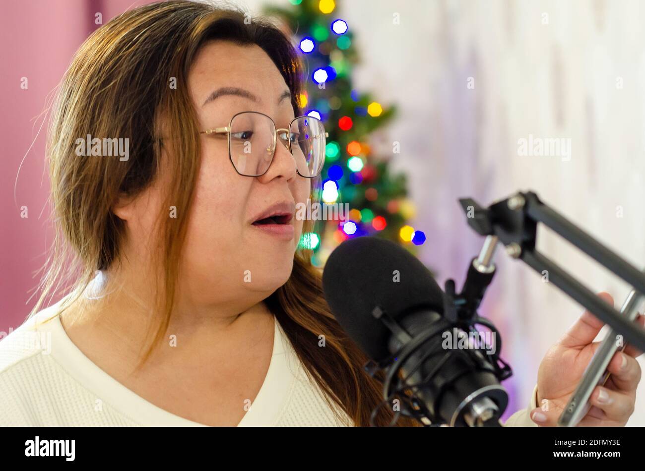 A lady singing into a microphone, recording vocals for a song. Stock Photo