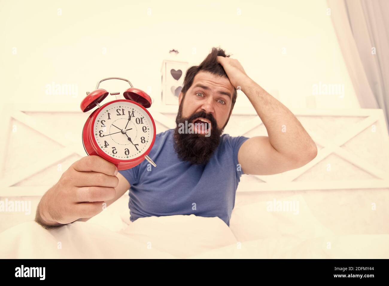 Stress concept. Man awake unhappy with alarm clock ringing. Insomnia