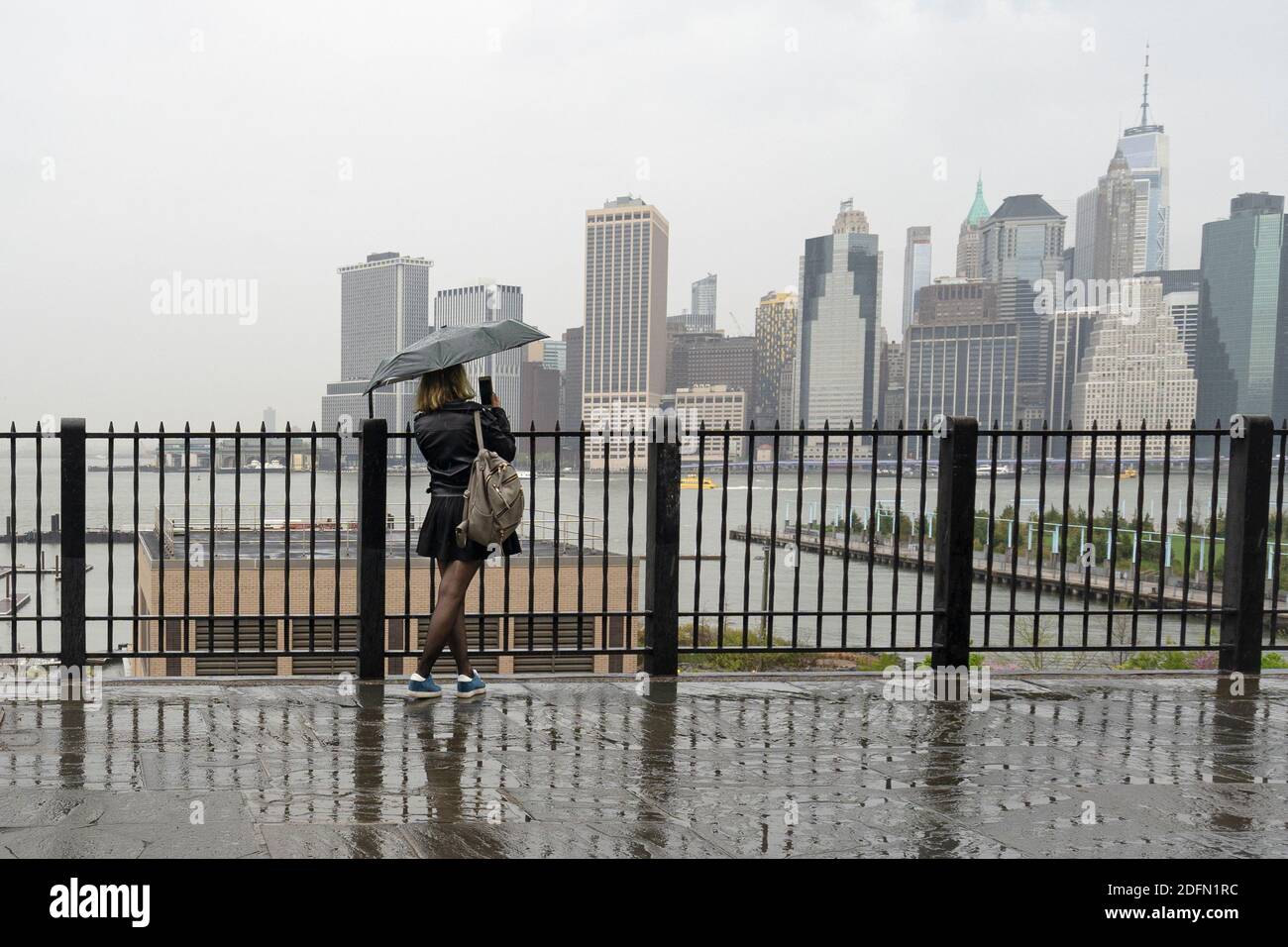 Woman holding an umbrella looking out towards Manhattan, NY Stock Photo