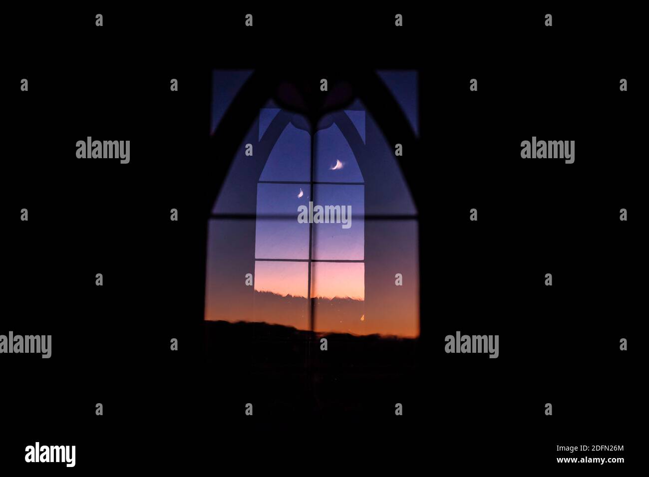 Double exposure of a crescent moon through a window at the Stations of the Cross Shrine, San Luis, Colorado, USA Stock Photo