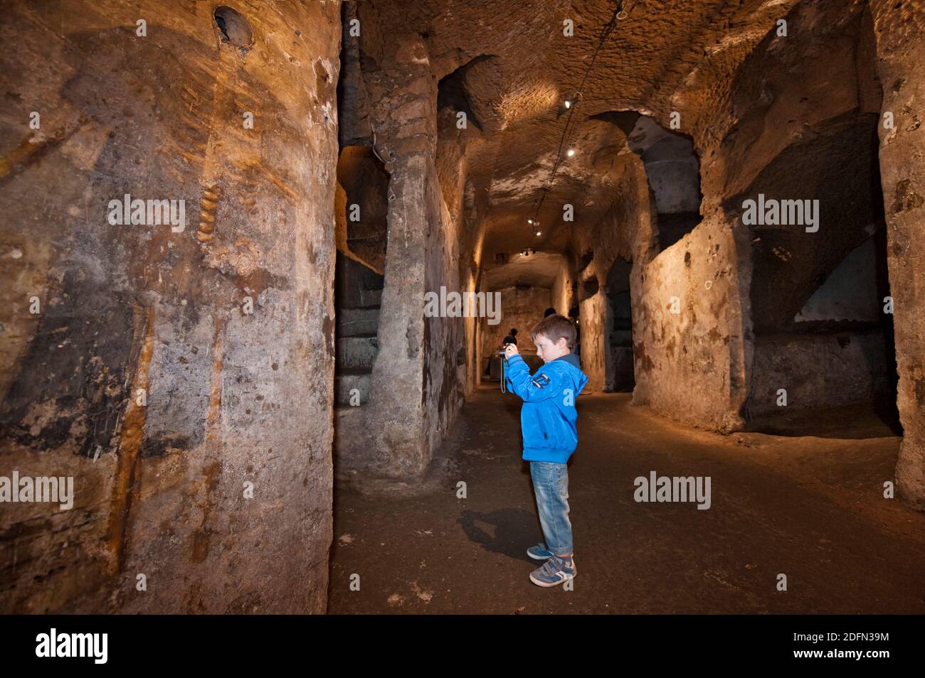 Young boy taking a picture of a fresco in Catacombe di San Gaudioso, Naples Stock Photo