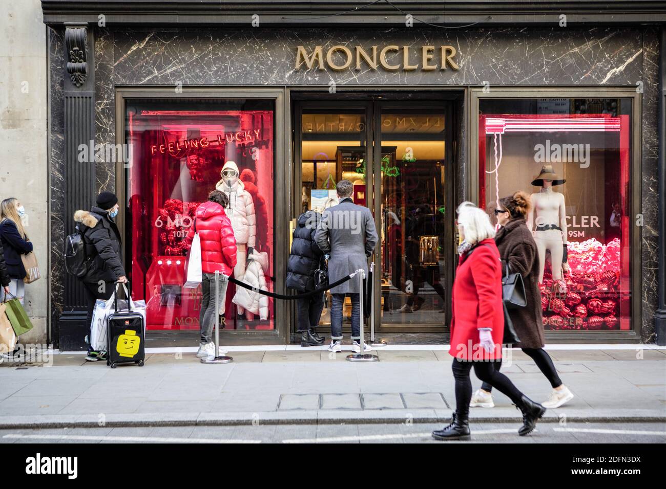 Shoppers queue outside Moncler store in Old Bond Street. People have  started flocking to central London as the capital has been placed in tier 2  on 2nd December after a month national