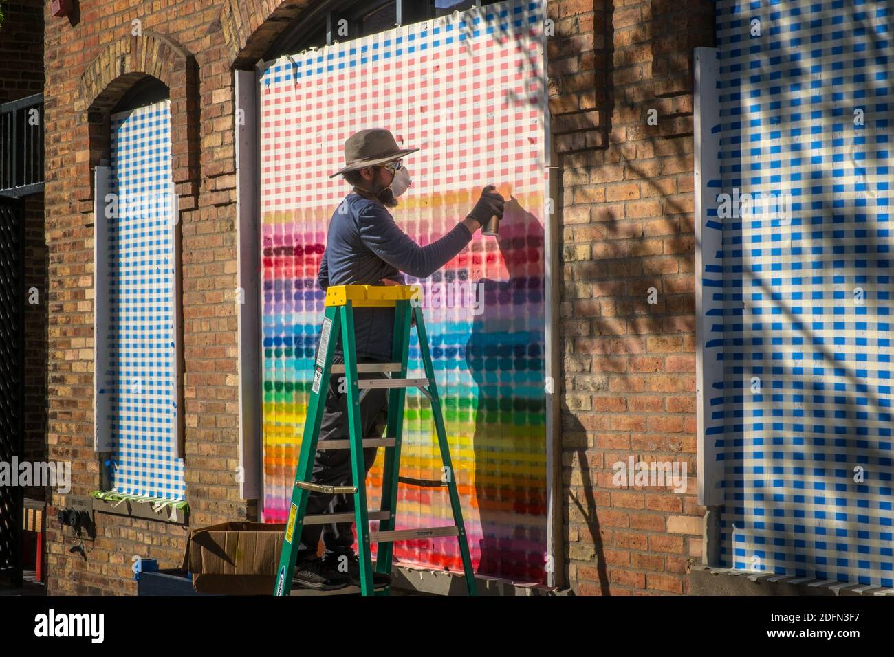 A man creates a colorful pattern while boarding up his business in downtown Minneapolis during the George Floyd riots Stock Photo