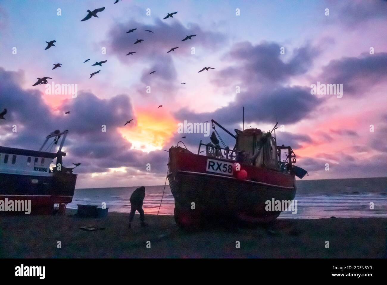 Hastings, East Sussex. 5th December 2020. Seagulls swirl at dawn over Hastings fishing boats with a colourful sunrise over the English Channel, on the day of Boris Johnson's talks with EU President of the European Commission, Ursula von Leyen,  to try to break the deadlock over Brexit fishing rights in British waters and secure a last minute trade deal. UK EU. Winter sunrise UK Stock Photo
