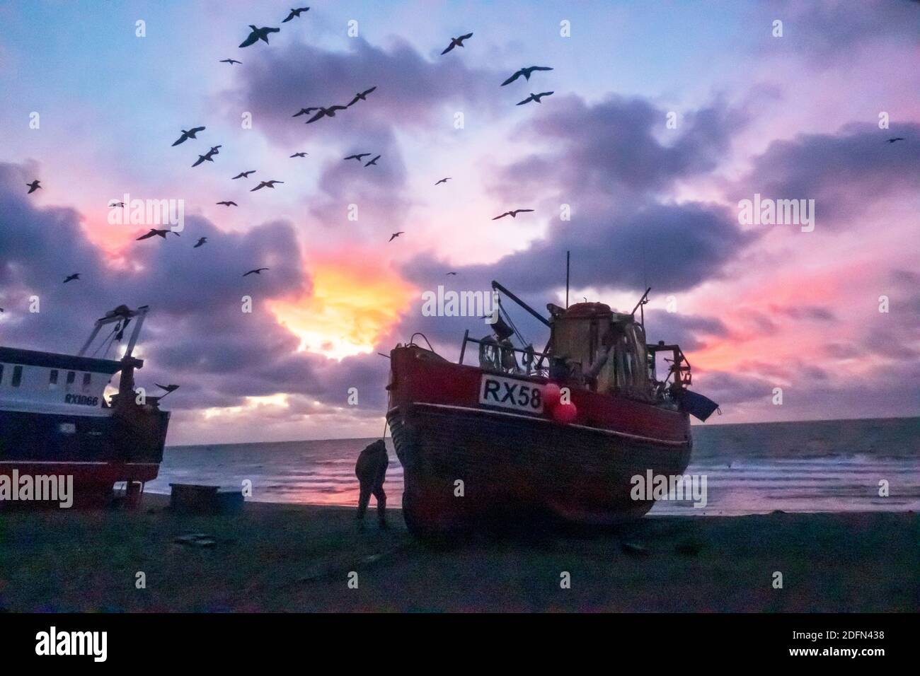 Hastings, East Sussex. 5th December 2020. Seagulls swirl at dawn over Hastings fishing boats, with a colourful sunrise over the English Channel, on the day of Boris Johnson's talks with EU President of the European Commission, Ursula von der Leyen, to try to break the deadlock over Brexit fishing rights in British waters and secure a last minute trade deal. UK, EU. Winter sunrise UK Stock Photo