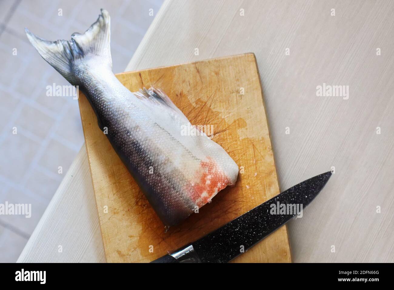 On the cutting Board is a piece of fish and a knife. The cooking process of the fish.  Stock Photo