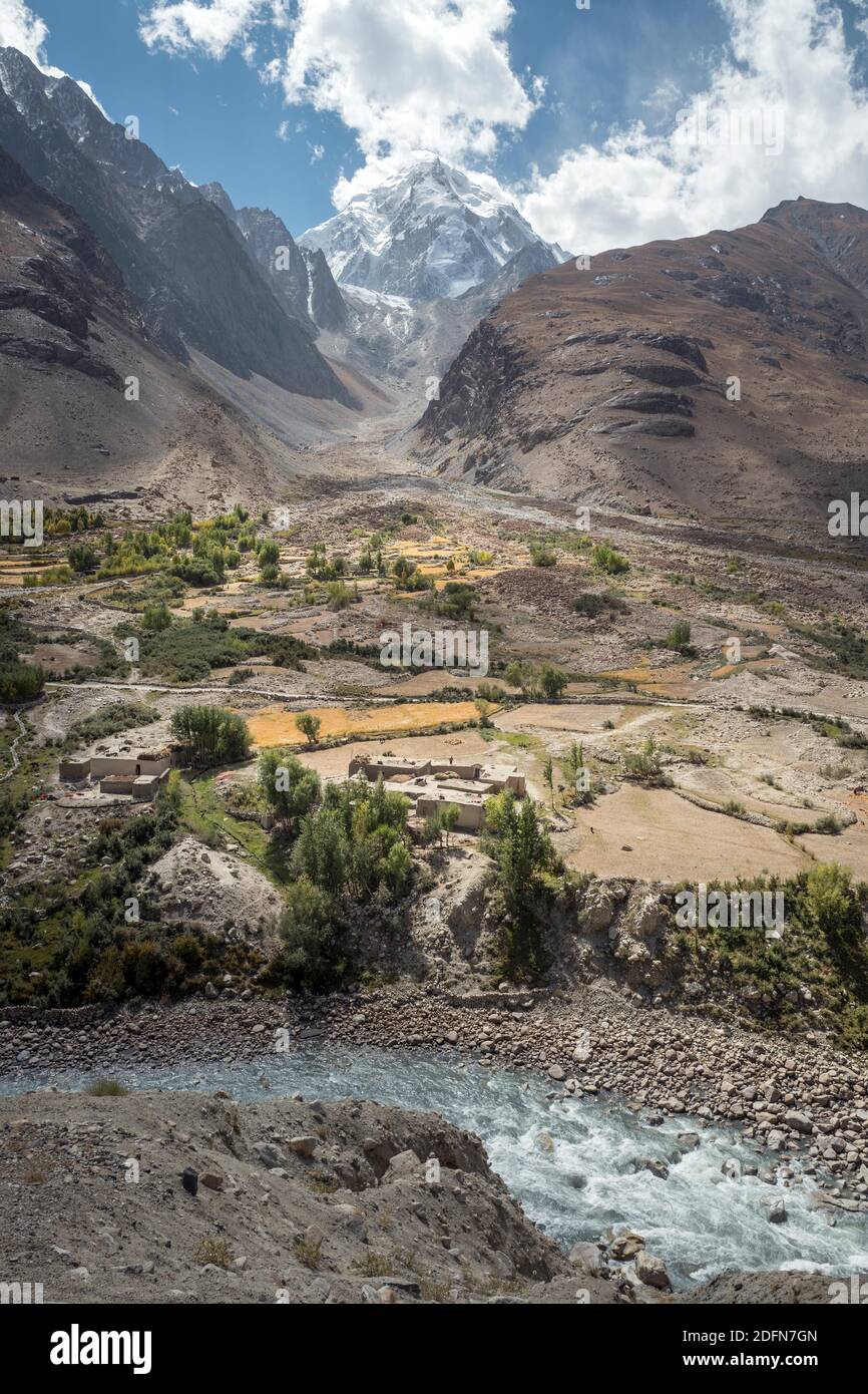 View of the homestead of a farmer's family, grain fields, in front the river Pandsch, behind it a snow-covered peak of the Hindu Kush, Khandud Stock Photo