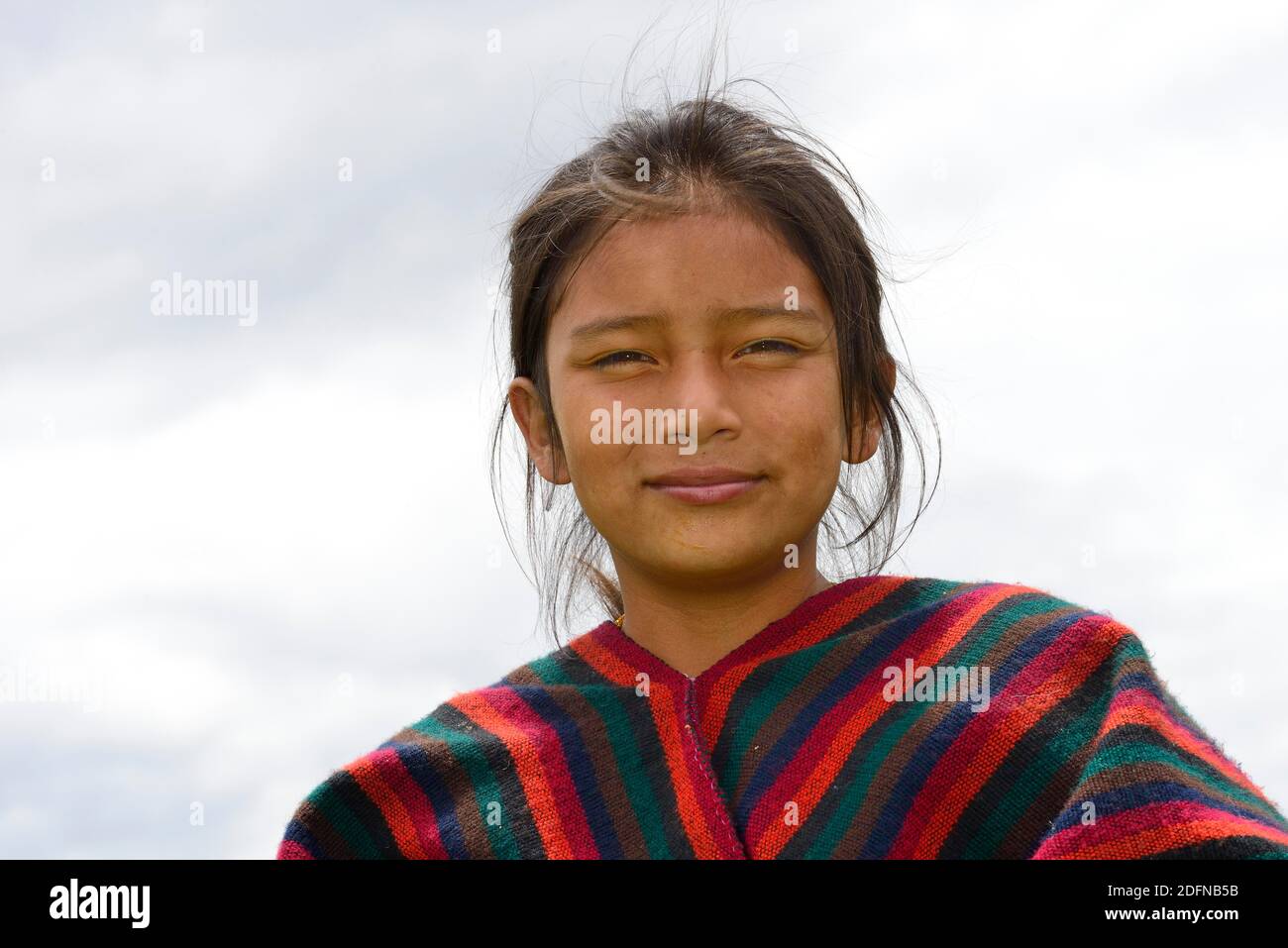 Indigenous girl looks smiling into the camera, near Otavalo, Imbabura province, Ecuador Stock Photo