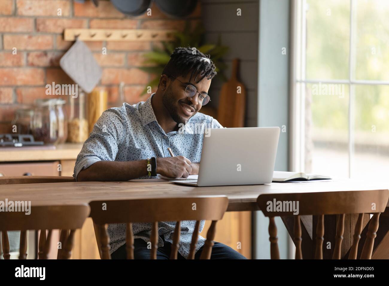 Happy young mixed race man enjoying learning distantly. Stock Photo