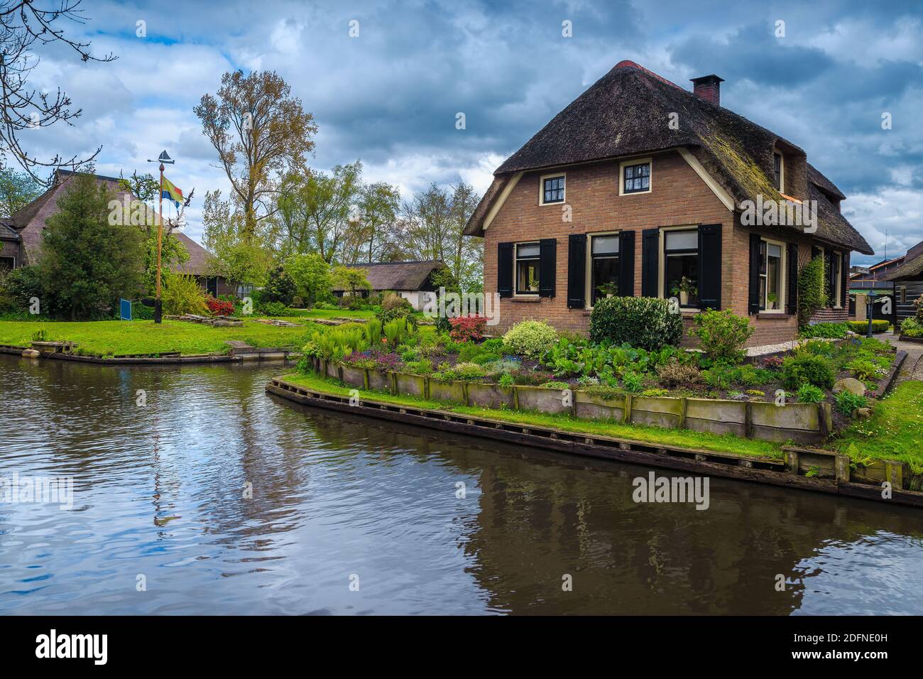 Admirable waterfront house and stunning small ornamental garden with colorful flowers, Giethoorn, Netherlands, Europe Stock Photo