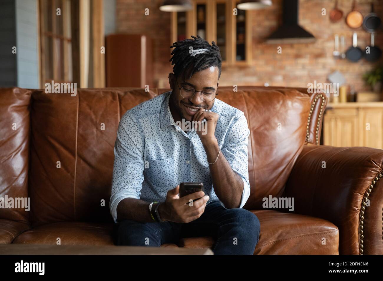 Smiling young african ethnicity guy using smartphone. Stock Photo