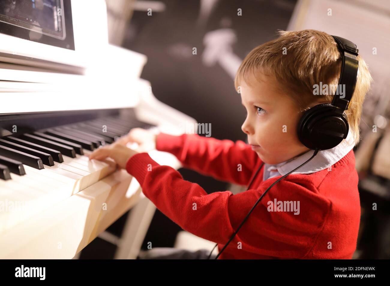 Child with headphones playing the piano in music class Stock Photo Alamy