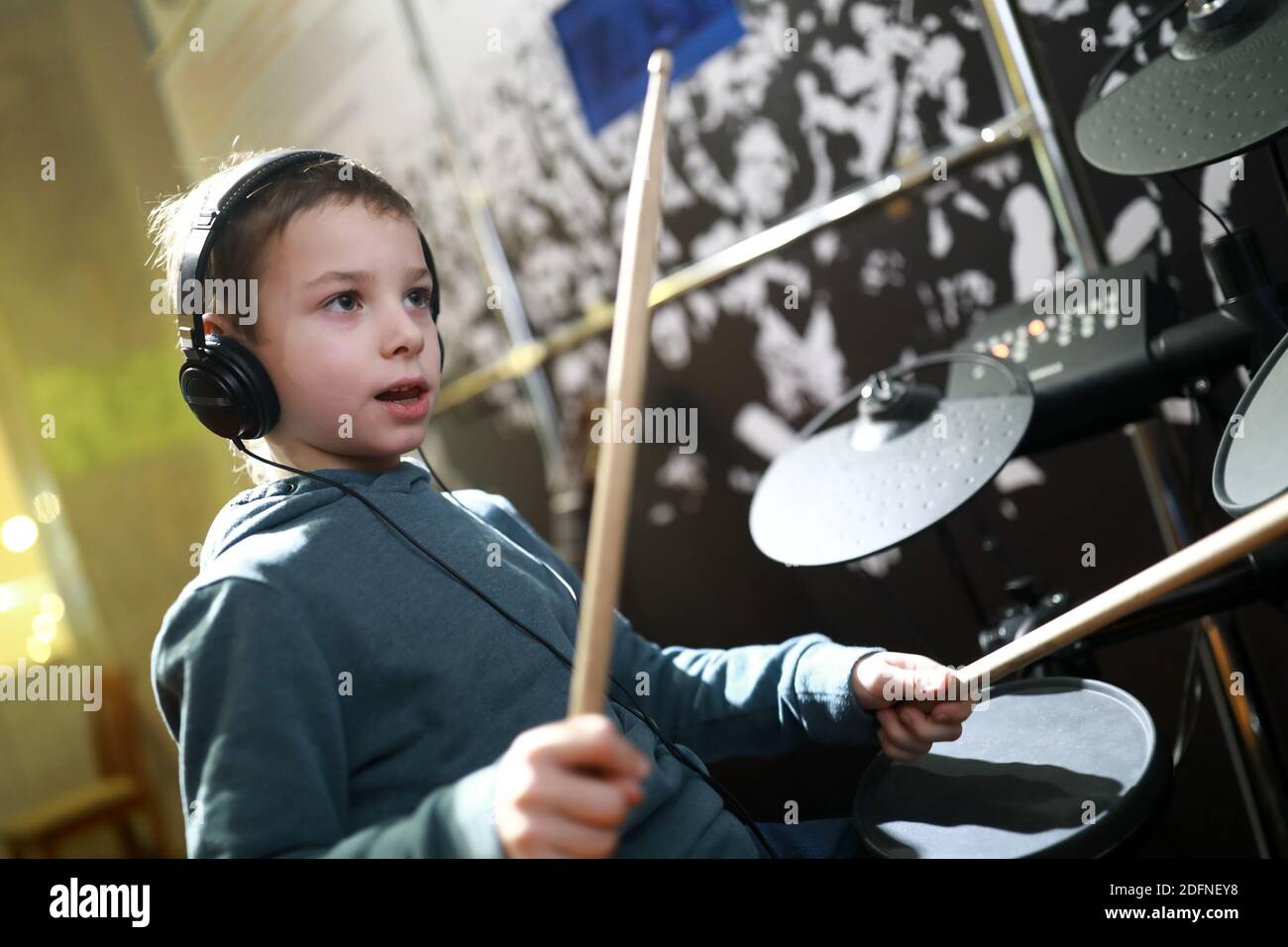 Serious boy with headphones playing drums in music class Stock Photo