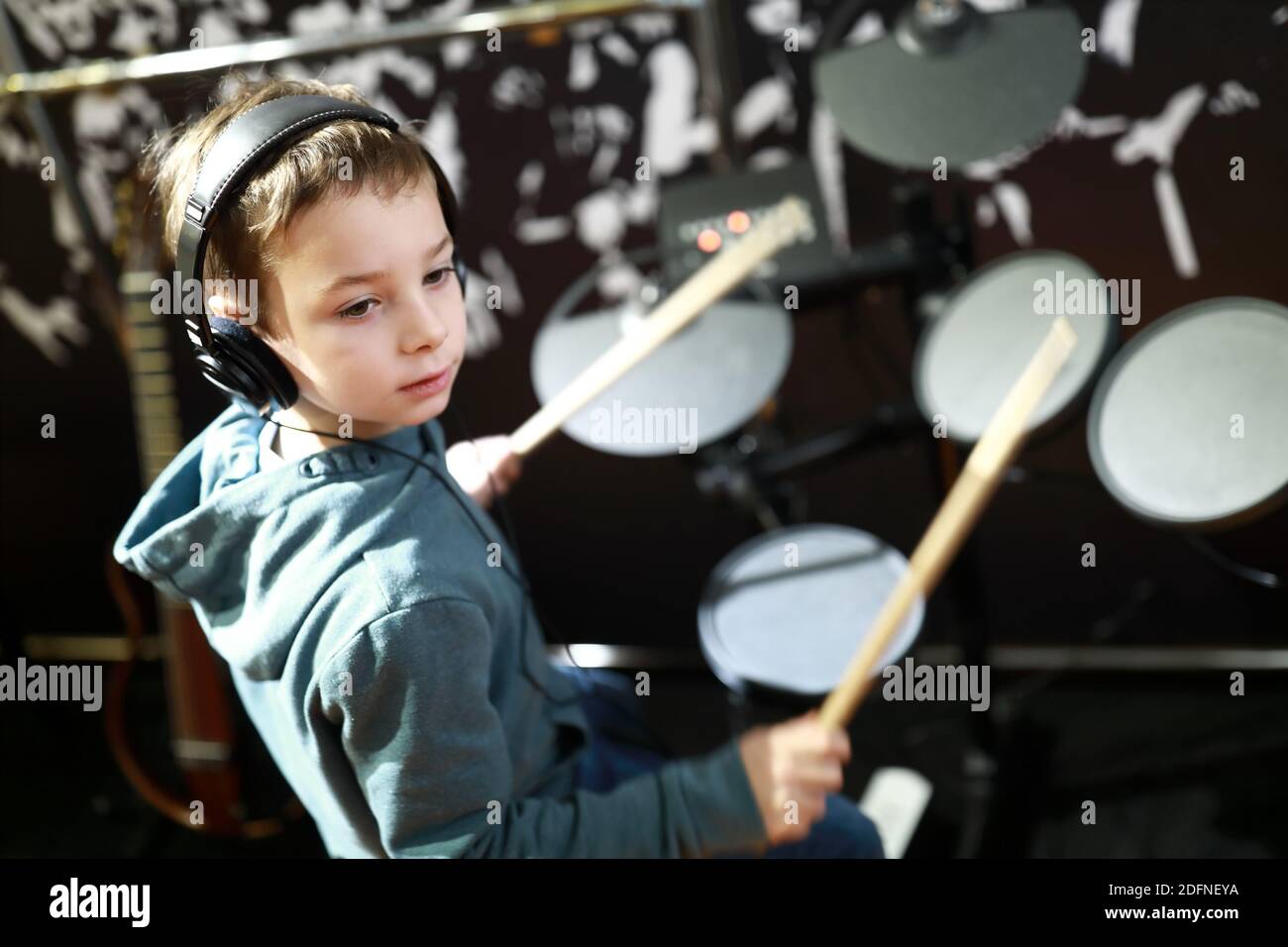Kid with headphones playing drums in music class Stock Photo Alamy