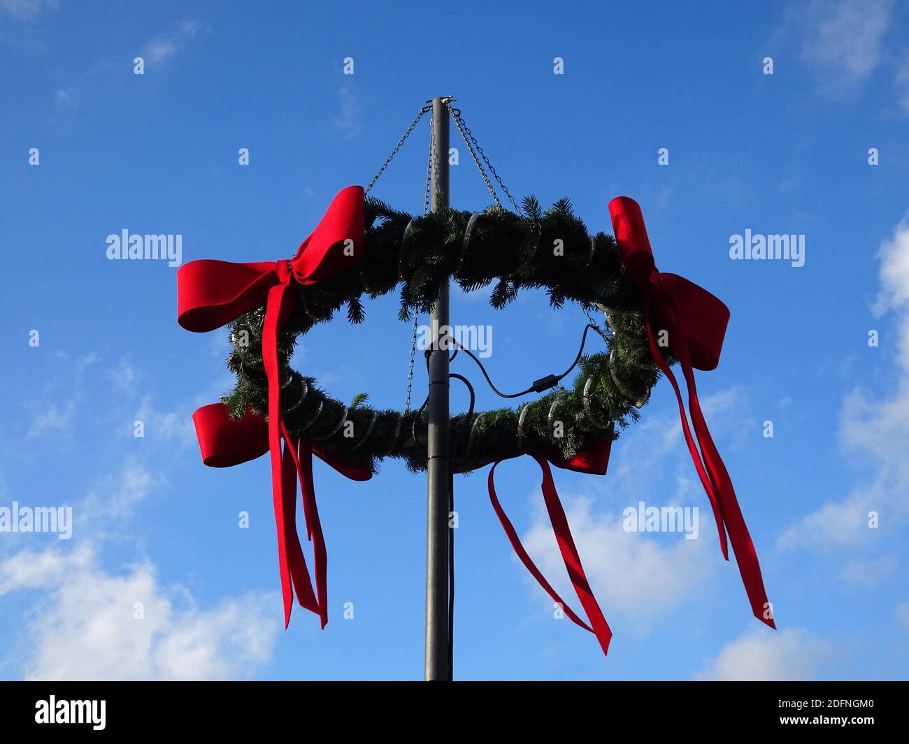 Christmas wreath with fir branches and a red ribbons on a pole. Blue ...