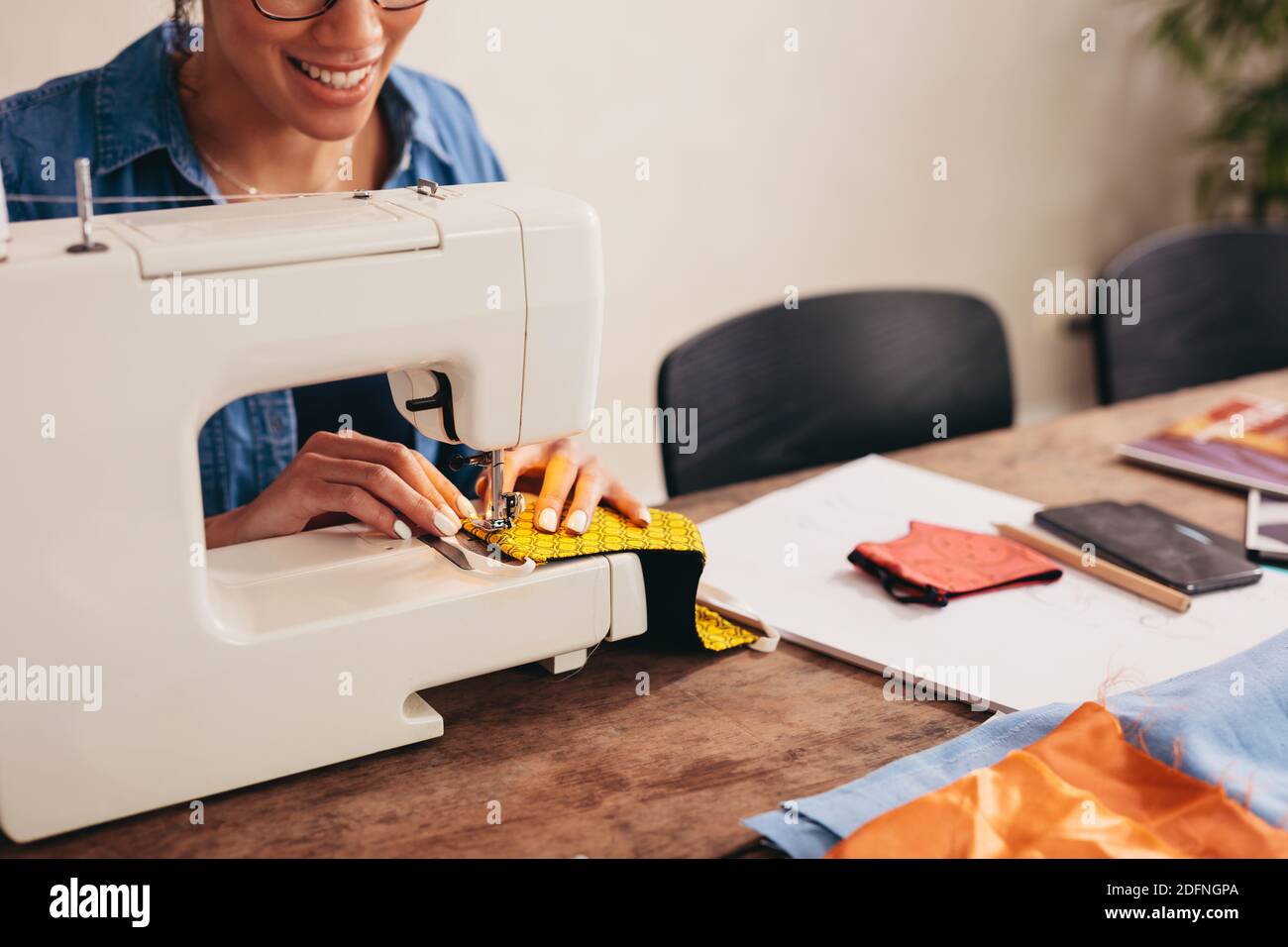 Woman hands sewing a face mask at home. Woman using the sewing machine to sew the face masks at home. Stock Photo