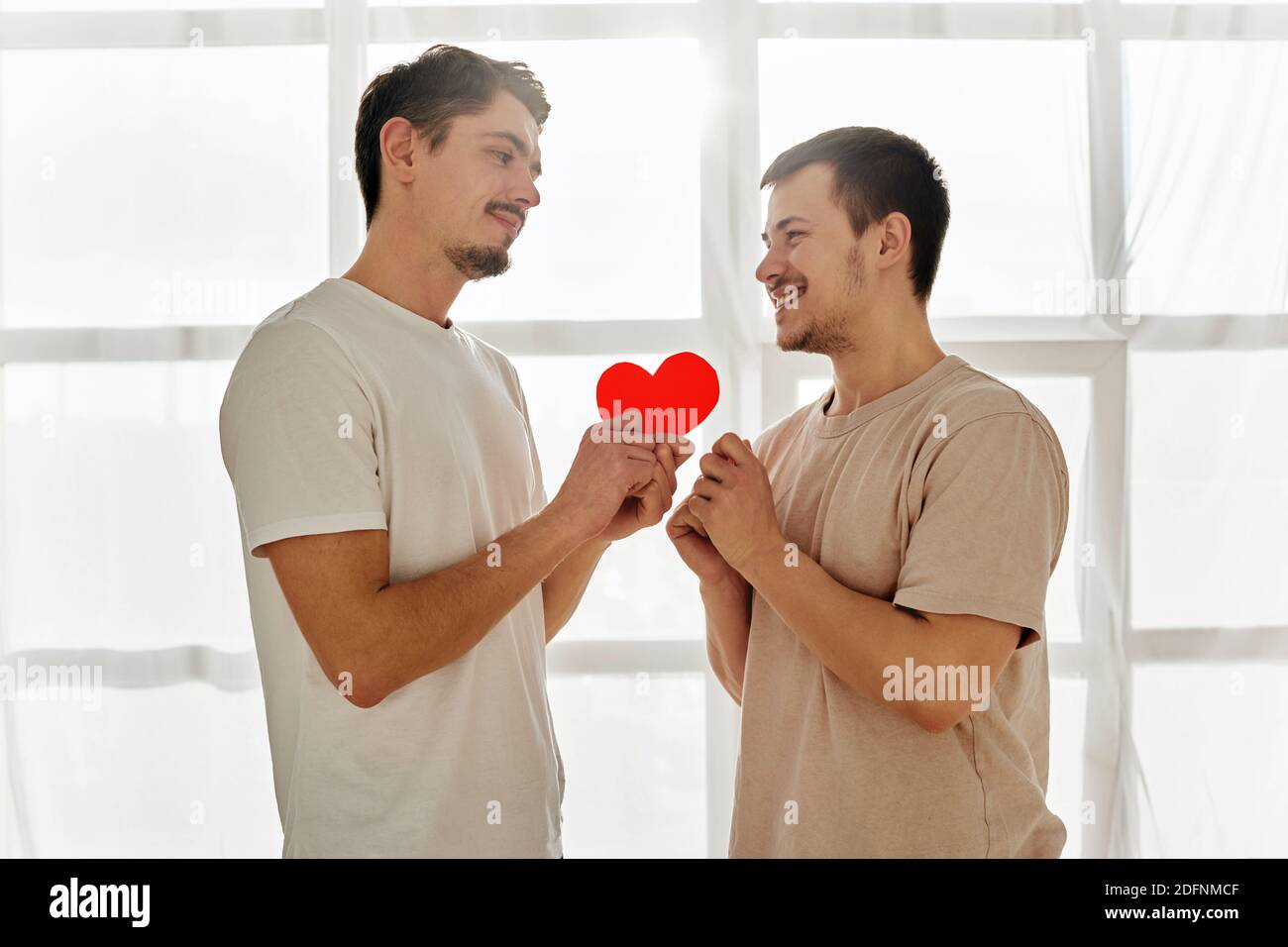 Gay couple celebrating valentine's day. A guy gives a valentine to man at home Stock Photo