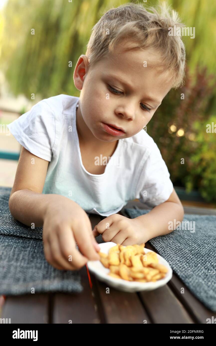 Child eating crackers at table in cafe Stock Photo Alamy