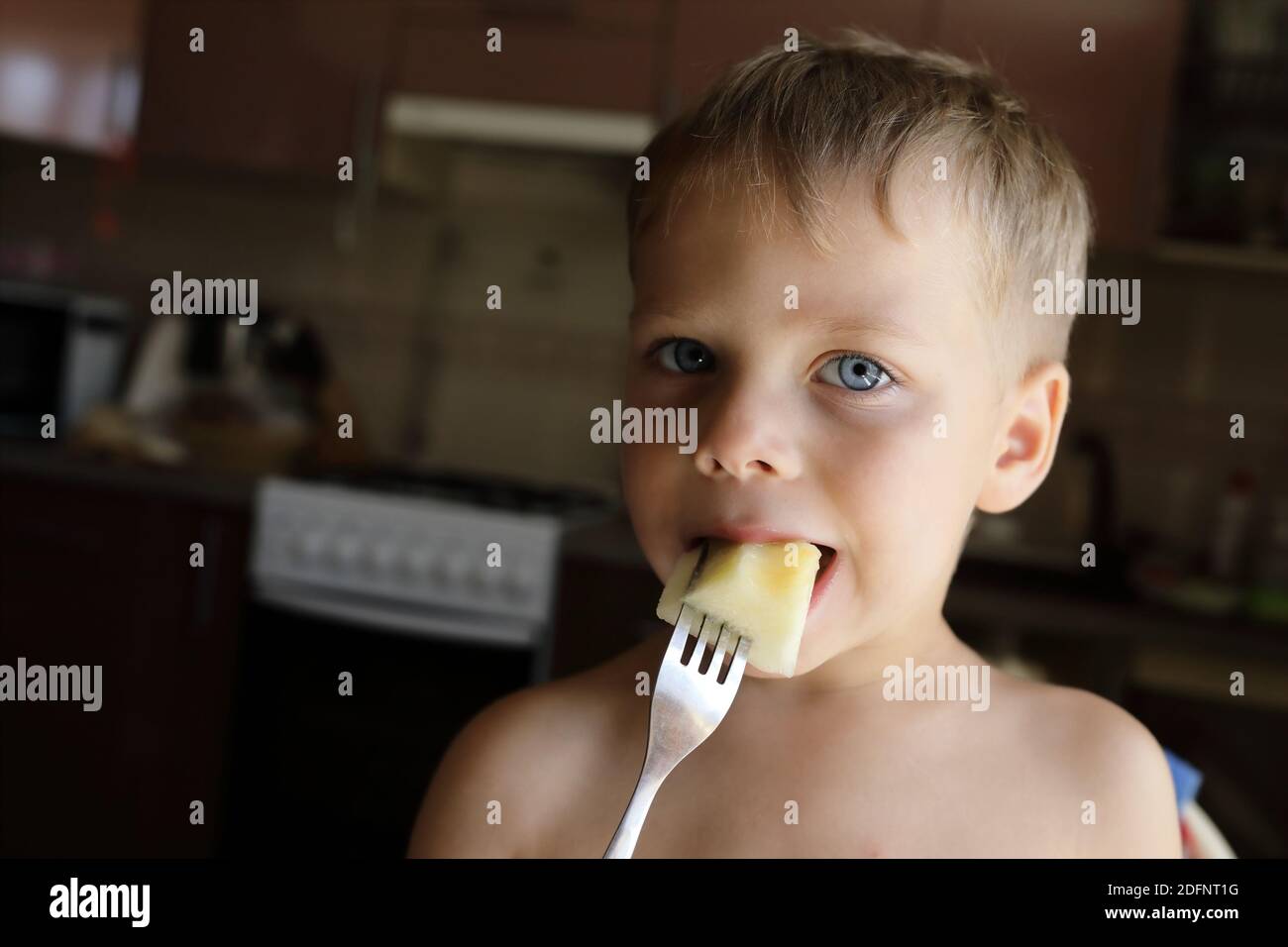 Child eating melon with fork in the kitchen Stock Photo - Alamy