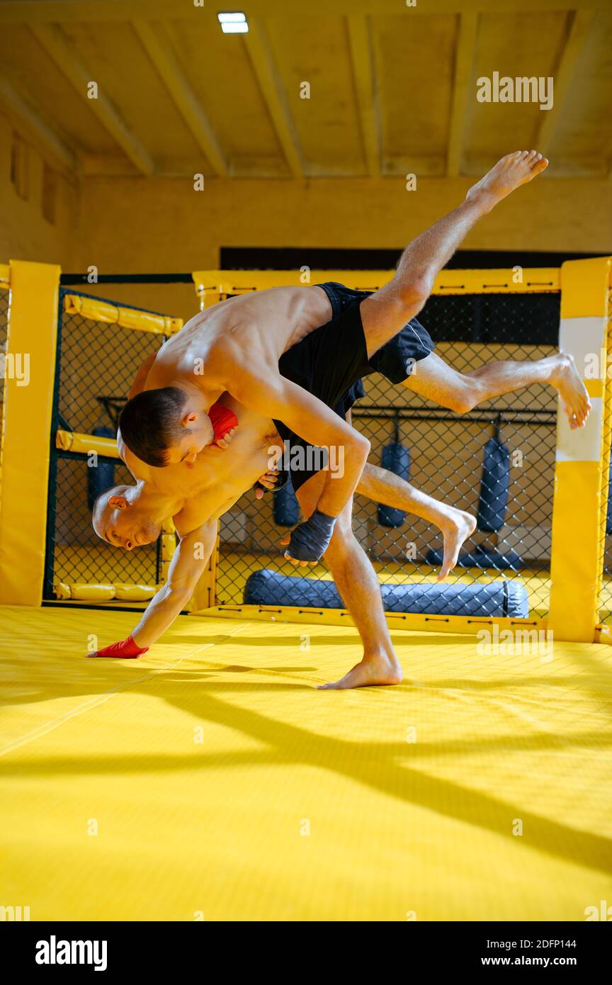 Two male MMA fighters fights in a cage Stock Photo